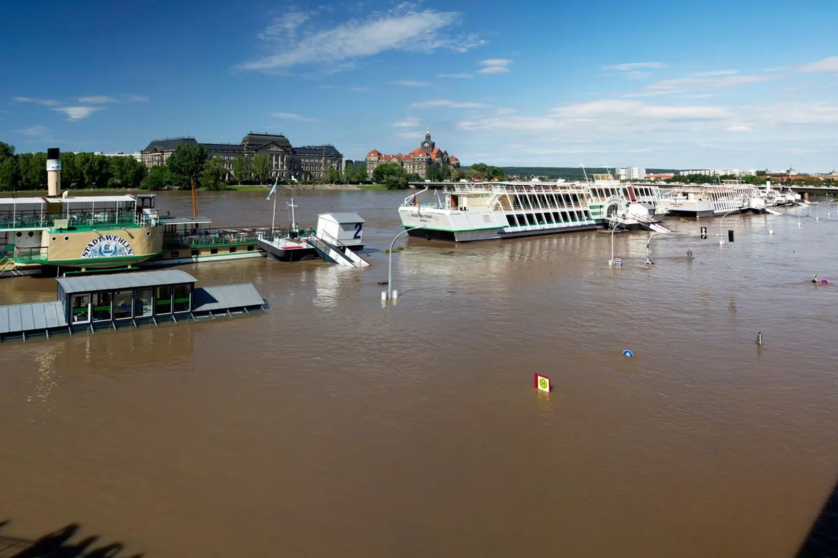 Quai de rivière inondé où flottent des bateaux amarrés