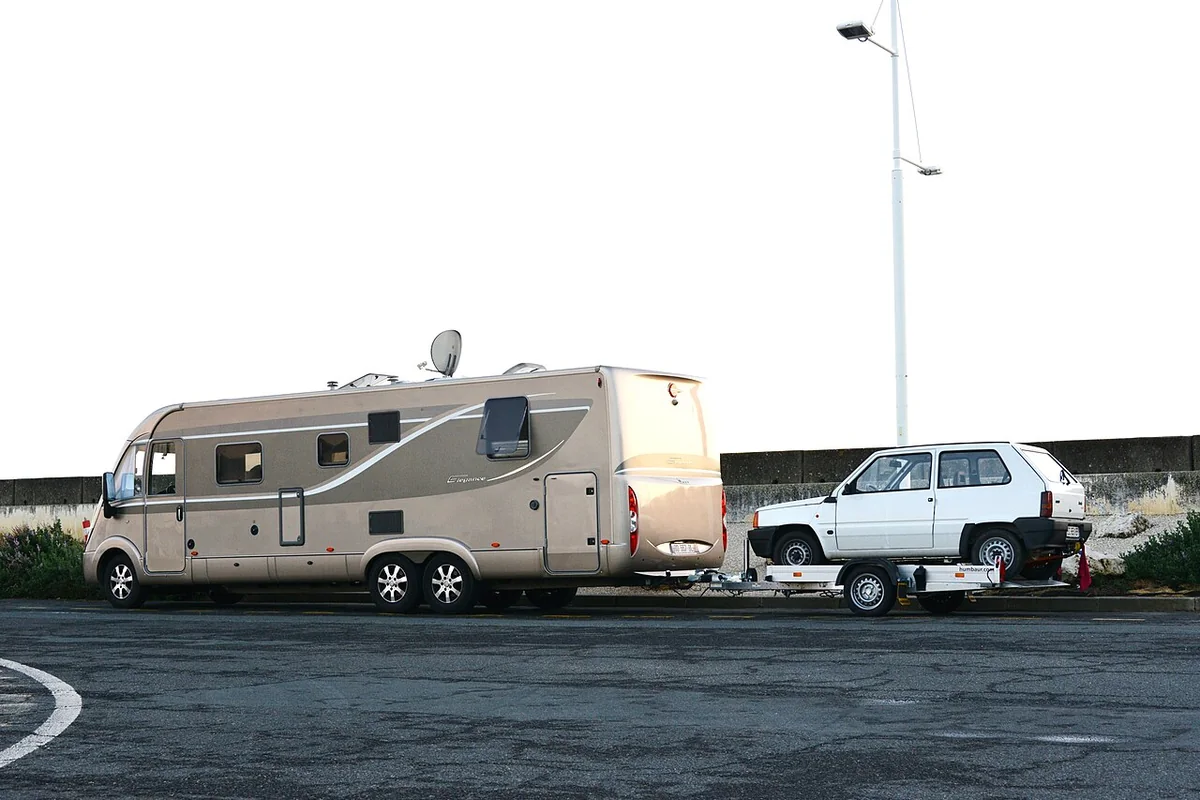 Camping-car avec sa voiture tractée sur une aire